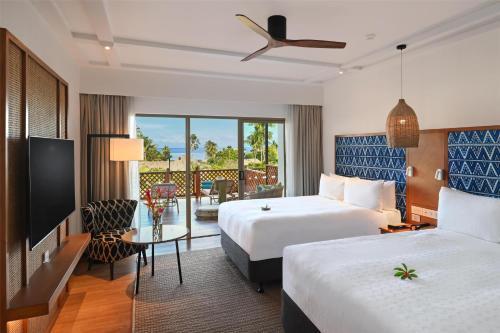 a hotel room with two beds and a balcony at Outrigger Fiji Beach Resort in Korotogo