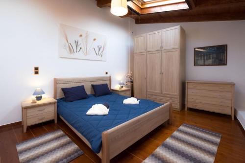 a bedroom with a blue bed and a wooden floor at Gaby's charming house in Kavoúsion