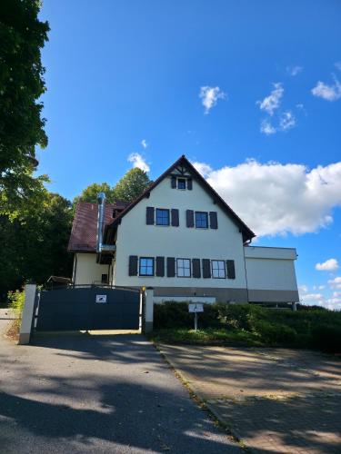 a white house with a gate in front of it at Berggasthof & Hotel Götzinger Höhe in Neustadt in Sachsen