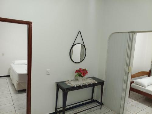 a mirror and a table with a vase of flowers on it at Casa espaçosa, com ar condicionado em todos os quartos in Barra do Garças