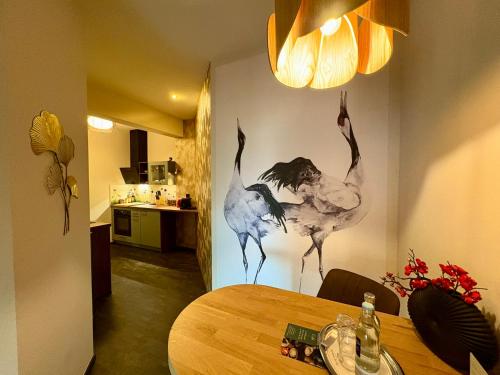 ein Esstisch mit einem Vogelgemälde an der Wand in der Unterkunft Deluxe Apartment mit Balkon und Frühstück im Hotel Reindahls in Wilkendorf