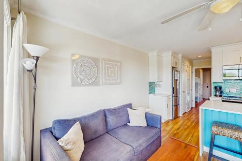 a living room with a blue couch and a kitchen at Sea Cabin 227-B in Isle of Palms