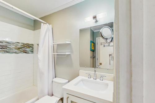 Un baño con lavabo, inodoro y espejo. en Sea Cabin 227-B, en Isle of Palms