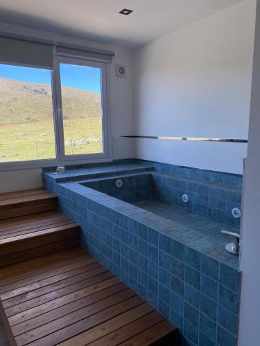 a blue tiled tub in a room with a window at Pie de Piedra Hotel Boutique in Sierra de la Ventana