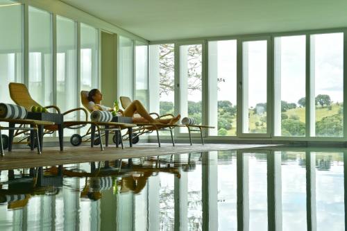 a woman sitting in chairs next to a swimming pool at Pousada Convento de Arraiolos in Arraiolos