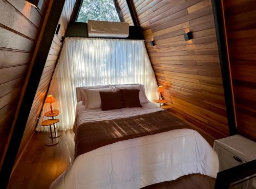 a bed in a small room with a window at Na Mata Cabanas in Foz do Iguaçu