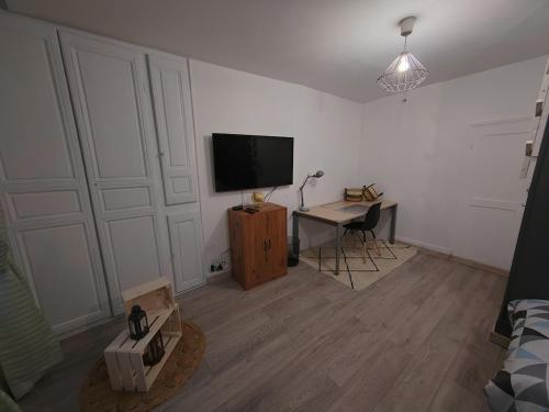 a living room with a flat screen tv and a desk at Maison de ville spacieuse in Dammartin-en-Goële