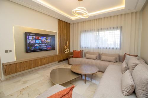a living room with a couch and a table and a tv at Calme & Cocon Apartment Near Airport in Nouaceur