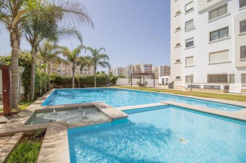 a swimming pool in front of a building at Calme & Cocon Apartment Near Airport in Nouaceur
