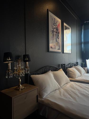 a bedroom with two beds and a lamp on a night stand at Apartments24 Black 1903 in Rakvere