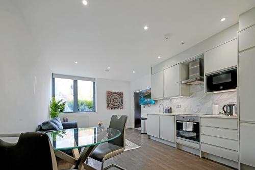 a kitchen and living room with a glass table at Milburn Retreat in Milton Keynes