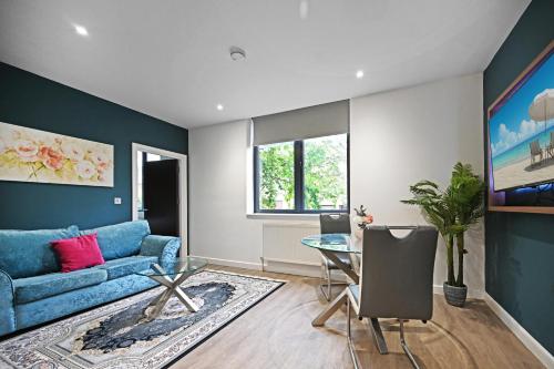 a living room with a blue couch and a glass table at Milburn Retreat in Milton Keynes