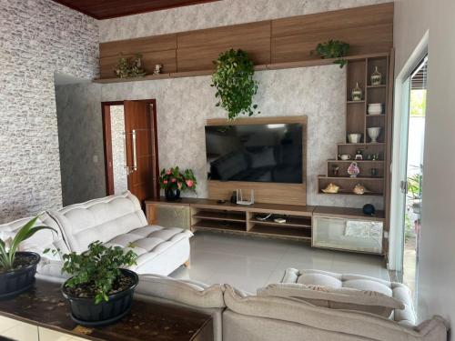 a living room with white furniture and a flat screen tv at CASA OUTEIRO da GLORIA in Porto Seguro