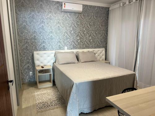 a small bedroom with a bed and a table at CASA OUTEIRO da GLORIA in Porto Seguro