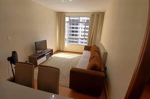 a living room with a couch and a television at Conforto familiar – Wi-Fi veloz e 1 min da praia in Santos