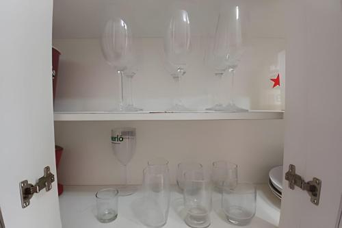 a row of wine glasses sitting on a shelf at Conforto familiar – Wi-Fi veloz e 1 min da praia in Santos