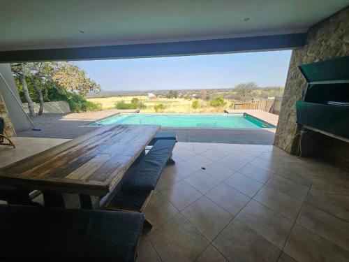 Una mesa de madera frente a una piscina. en Euphoria Self Catering Home, en Mookgophong