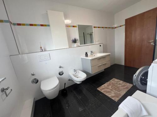 a white bathroom with a toilet and a sink at Exklusive Wohnung für 8 Personen mit großem Balkon in Niestetal
