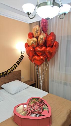 a bunch of red balloons in a box on a bed at Сонячна Соната in Polyana