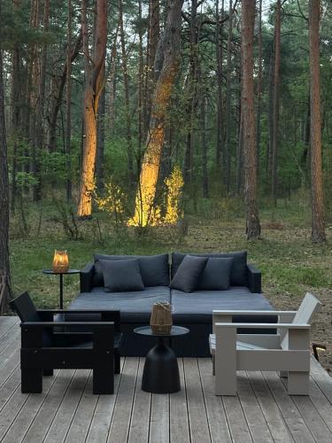 a couch and tables on a deck with a forest at HATTA Las in Gąsiorowo Duże