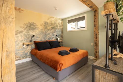 a bedroom with a bed with an orange blanket at B&B Het Boompje in Wervershoof