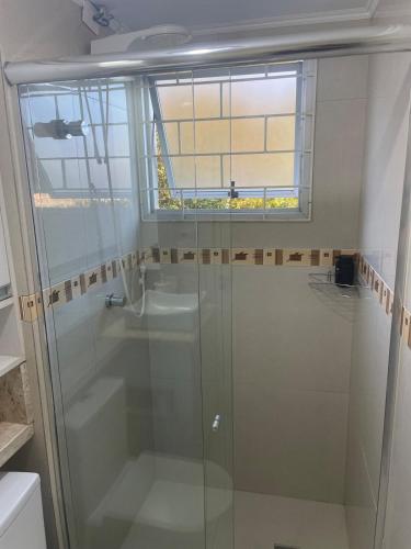 a glass shower in a bathroom with a window at AP prox Unisinos-Trem com 2 AC e 2 smart TV in São Leopoldo