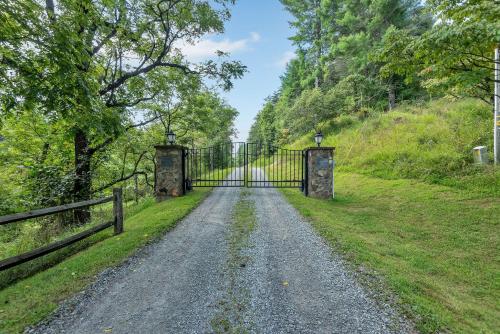 an open gate on a gravel road with a fence at Cabin on New River, Fire Pit, Dogs OK, Hot Tub with VIEWS - Sleeps 10 in Piney Creek
