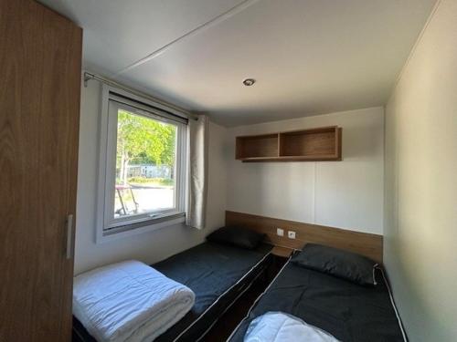 ein kleines Schlafzimmer mit zwei Betten und einem Fenster in der Unterkunft Camping bois Dormant, 4 étoiles 85 st jean de mont in Saint-Jean-de-Monts