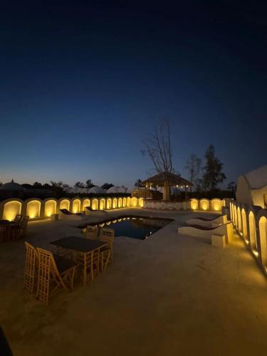 a pool with chairs and a bridge at night at Gazrashek Siwa Hot spring& trips Haven in Siwa