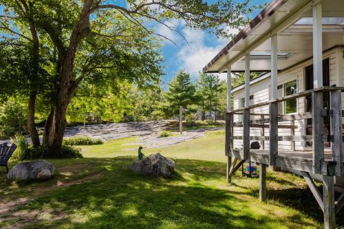 ein weißes Haus mit einer Veranda und einem Baum in der Unterkunft Georgian Bay Rockwood 3-bdrm Waterfront Cottage #2 in Dillon