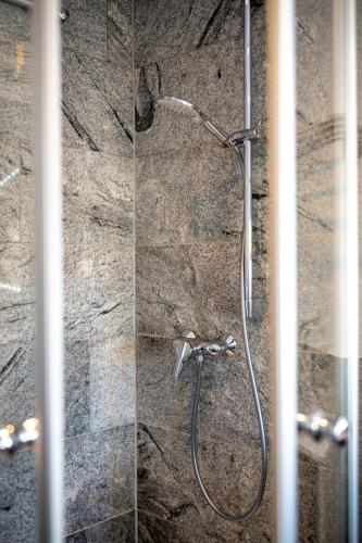 a shower in a bathroom with a stone wall at Dachgeschosswohnung mit Klimaanlage-15min vom Europa Park entfernt in Kenzingen