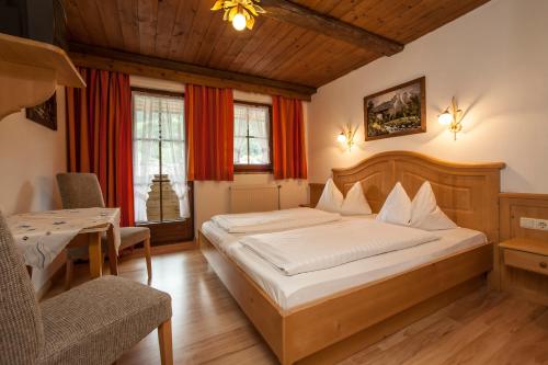 1 dormitorio con 1 cama grande, mesa y sillas en Kaiserpension Müllnerhof, en Oberndorf in Tirol