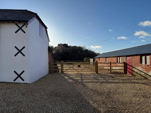 a white barn with crosses on it next to a fence at New Close Farmhouse in Bransgore