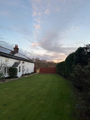 a large yard next to a white house with a green lawn at New Close Farmhouse in Bransgore