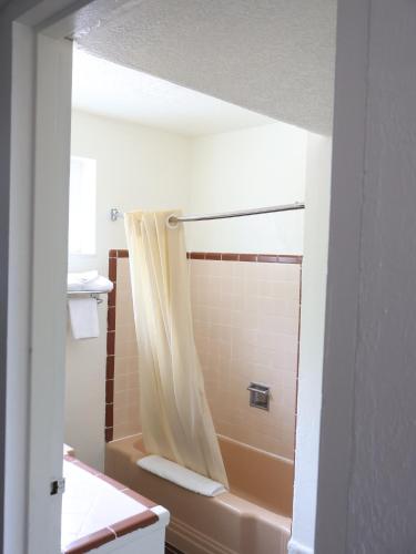 a bathroom with a tub and a shower curtain at Downtown Inn in Albuquerque