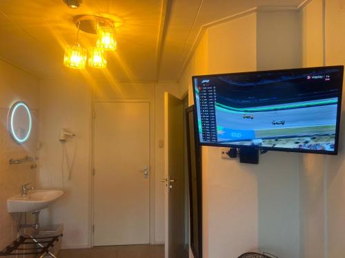 a bathroom with a flat screen tv on the wall at Hotel-Eetcafé d'Olde Heerd in Balkbrug