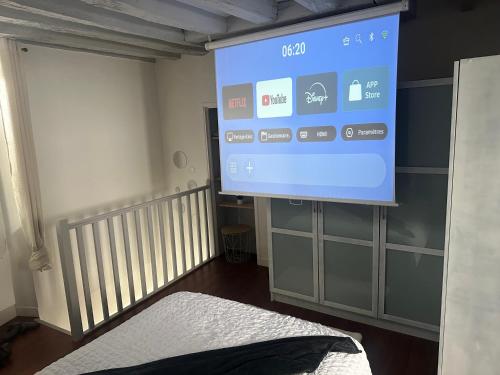 a large screen in a room with a bed at Charmant appartement au coeur de Rueil-Malmaison in Rueil-Malmaison