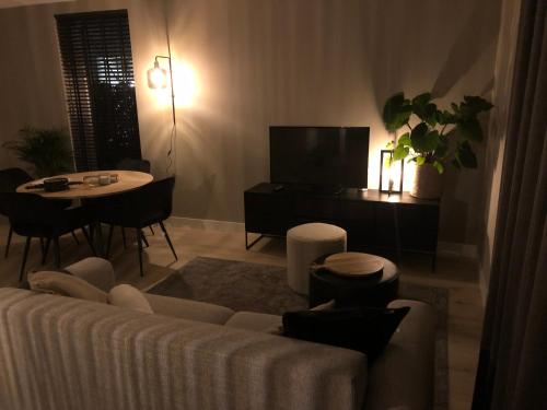 a living room with a couch and a table at Luxe appartement dichtbij strand en zee, in het hart van de bollenstreek in Noordwijkerhout