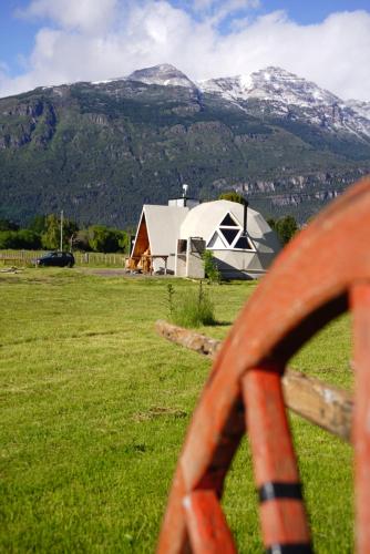 a barn in a field with mountains in the background at Nomade Patagonia Glamping & Domos in Trevelin
