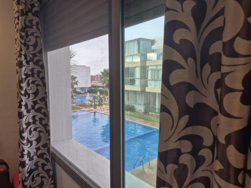 a window with a view of a swimming pool at Appart pour Famille balnéaire Accés direct à la Mer in Sidi Rahal