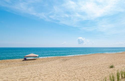 a beach with an umbrella and the ocean at Out of the Blue in Kitty Hawk
