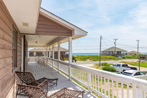 a porch with two chairs and a view of the ocean at Out of the Blue in Kitty Hawk