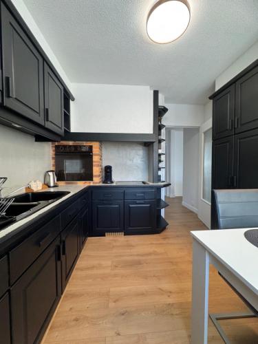 Una cocina con gabinetes negros y una encimera blanca. en Le 9 - Basel Airport, en Saint-Louis