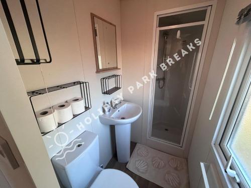 a small bathroom with a toilet and a sink at Cosy Cove at Seal Bay - 2 Bedroom Holiday Home on White Horse in Selsey