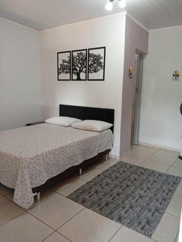 a bedroom with a bed and two pictures on the wall at Pousada Beija flor in Extrema