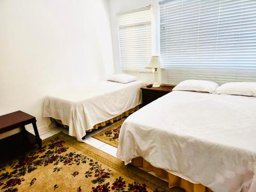 two beds sitting in a room with a window at Country Club House Retreat - 2 bedroom House with Pool near Montego Bay Airport and Beach Strip in Montego Bay