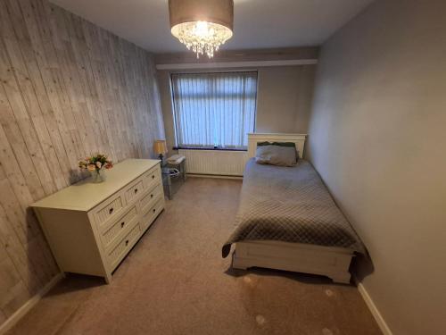 a bedroom with a bed and a dresser and a window at Gala House in Lurgan