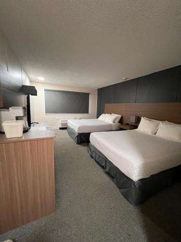 a hotel room with two beds and a flat screen tv at Capri Motor Inn in Smithers