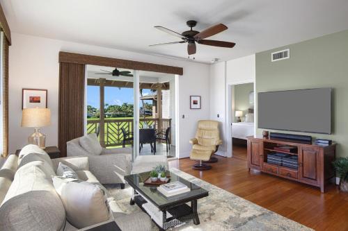 a living room with a couch and a flat screen tv at Poipu Retreat with Golf Ocean Views and AC in Koloa
