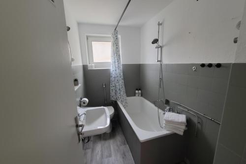 une salle de bain avec une baignoire, un lavabo et une fenêtre dans l'établissement L21-Apartment Geilenkirchen OT Teveren, 3 Zimmer, 6 Betten, Standardisierte Ausstattung, ideal für Reisende, Pendler, Familien, à Geilenkirchen